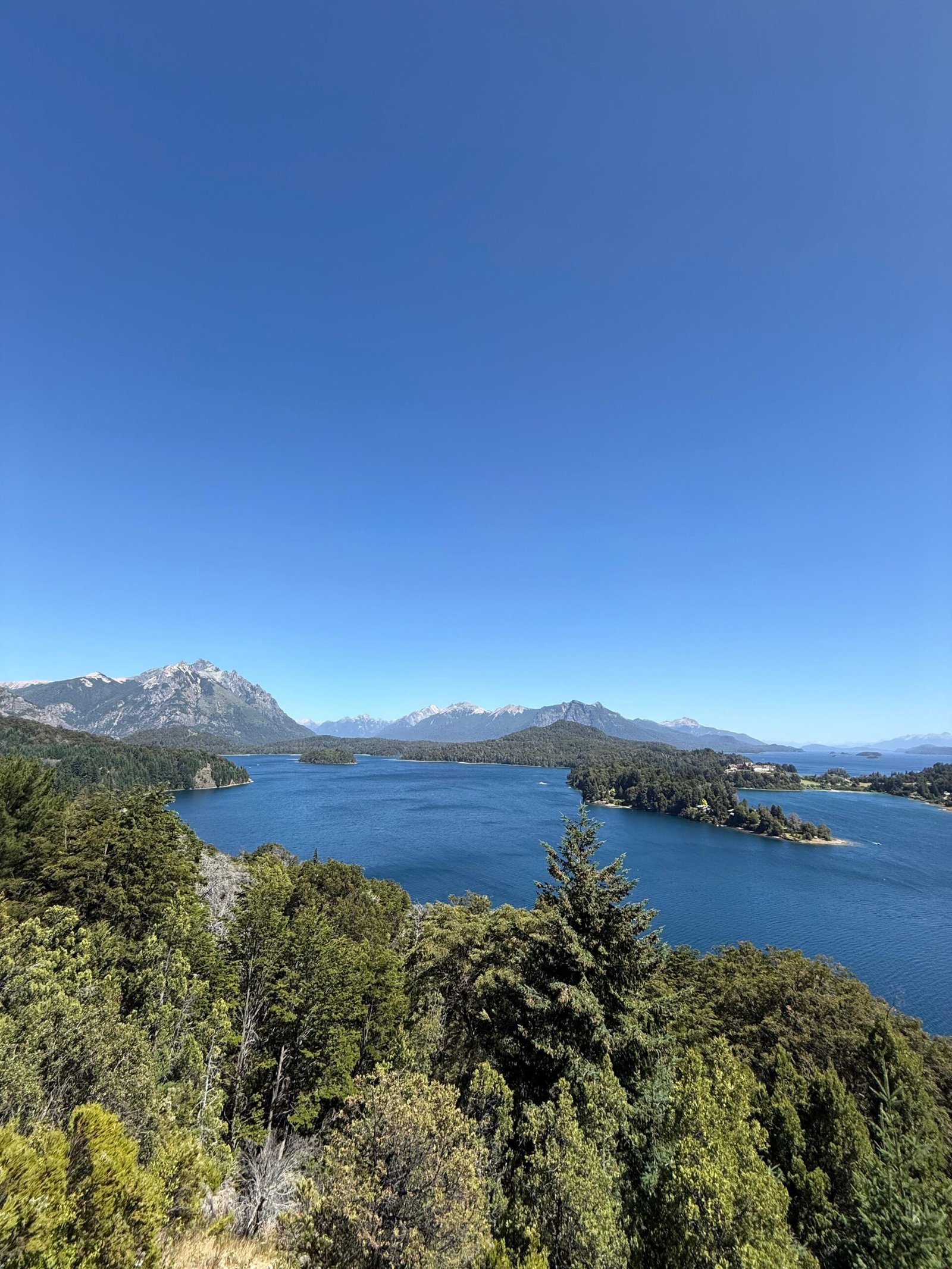 Vista panorâmica ensolarada dos lagos e montanhas no Circuito Chico em Bariloche.